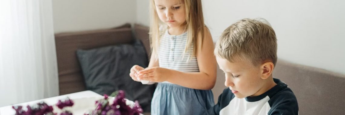 Young boy and girl playing with dough at a table, enjoying a fun indoor activity.
